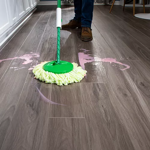 Dark wood-look flooring being cleaned after a spill with a mop